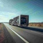 Open trailer car shipping truck carrying multiple vehicles on a U.S. highway